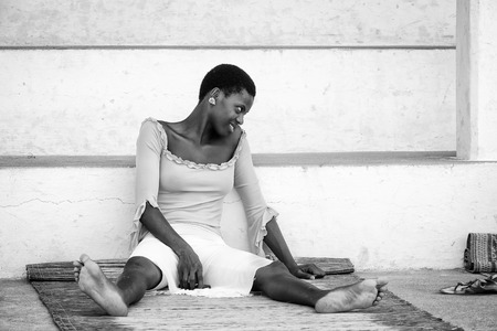 KARA, TOGO - MAR 9, 2013: Unidentified Togolese woman sits near a house. People in Togo suffer of poverty due to the unstable econimic situationのeditorial素材