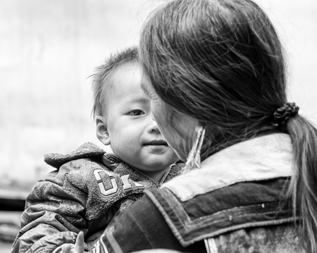 SAPA, VIETMAN - SEP 22, 2014: Unidentified Hmong little boy on his mother arms in Sapa, Vietnam. Hmong is a minority ethnic group of Vietnamのeditorial素材