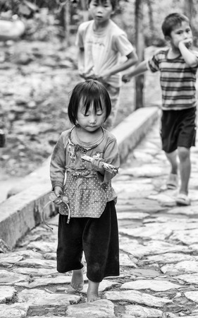 CATCAT VILLAGE, VIETMAN - SEP 12, 2014: Unidentified Vietnamese girl eats a candy in the Catcat village, Vietnam. 86 of Vietnamese people belong to the Viet ethnic groupのeditorial素材
