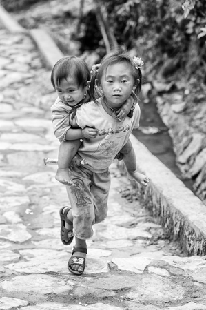CATCAT VILLAGE, VIETMAN - SEP 12, 2014: Unidentified Vietnamese beautiful girl carries her sister in the Catcat village, Vietnam. 86 of Vietnamese people belong to the Viet ethnic groupのeditorial素材