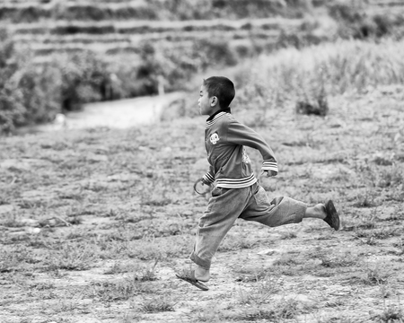 SAPA, VIETMAN - SEP 22, 2014: Unidentified Hmong boy runs on the grass in Sapa, Vietnam. Hmong is a minority ethnic group of Vietnamのeditorial素材