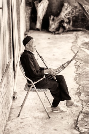LAO CHAI, VIETMAN - SEP 12, 2014: Unidentified Black Hmong man plays a traditional instrument in Lao Chai, Vietnam. Hmong is a ethnic minority group in Vietnamのeditorial素材