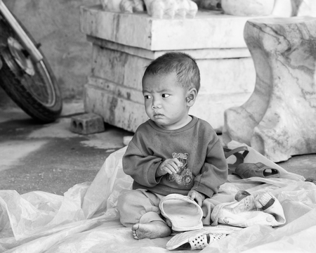 LAO CHAI, VIETMAN - SEP 12, 2014: Unidentified Black Hmong little boy near a house wall in Lao Chai, Vietnam. Hmong is a ethnic minority group in Vietnamのeditorial素材