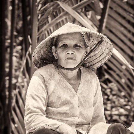 HO CHI MIN, VIETMAN - OCT 4, 2014: Unidentified Vietnamese woman in a rice hat portrait in Saigon, Vietnam. 86 of Vietnamese people belong to the Viet ethnic groupのeditorial素材