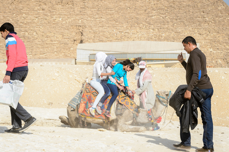 GIZA, EGYPT - NOV 23, 2014: Unidentified tourists ride a camel at Giza Necropolis, Egypt. UNESCO World Heritageのeditorial素材
