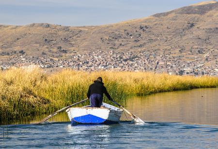 Man rows the boat over the Titicaca lake, Peru