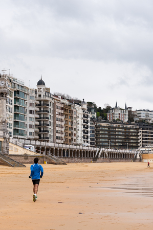 A young man runs over the Bay de la Concha, San Sebastian, Basque Country, Spainの写真素材
