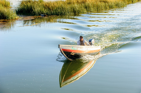 PUNO, PERU - NOV 7, 2010: Unidentified Uros man in a boat at the floating island (Isla Flotante), Titicaca lake. Popular touristic attraction in Peruのeditorial素材