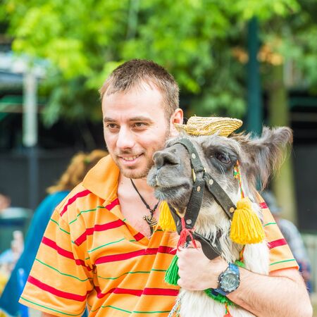 SANTIAGO, CHILE - NOV 1, 2014:  Unidentified Chilean man hugs a lama in the street. Chilean people are mainly of mixed Spanish and Amerindian descentのeditorial素材