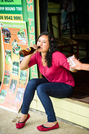 MINDO, ECUADOR - JAN 1, 2015: Unidentified Ecuadorian woman drink beer near the shop. 71,9% of Ecuadorian people belong to the Mestizo ethnic groupのeditorial素材