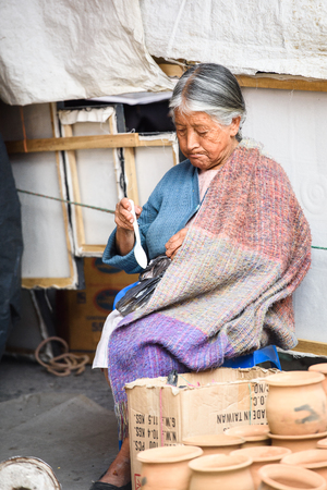 OTAVALO, ECUADOR - JAN 3, 2015: Unidentified Ecuadorian woman in traditional clothes works at the Otavalo Market. 71,9% of Ecuadorian people belong to the Mestizo ethnic groupのeditorial素材