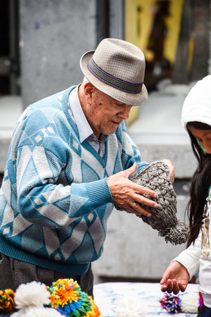 OTAVALO, ECUADOR - JAN 3, 2015: Unidentified Ecuadorian man tries to buy a hat at the Otavalo Market. 71,9% of Ecuadorian people belong to the Mestizo ethnic groupのeditorial素材