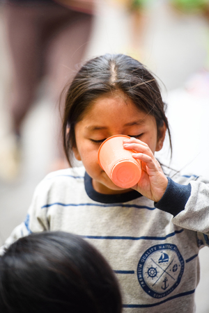 OTAVALO, ECUADOR - JAN 3, 2015: Unidentified Ecuadorian little girl drink a cold juice at the Otavalo Market. 71,9% of Ecuadorian people belong to the Mestizo ethnic groupのeditorial素材