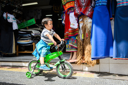 OTAVALO, ECUADOR - JAN 3, 2015: Unidentified Ecuadorian little boy on bike at the Otavalo Market. 71,9% of Ecuadorian people belong to the Mestizo ethnic groupのeditorial素材