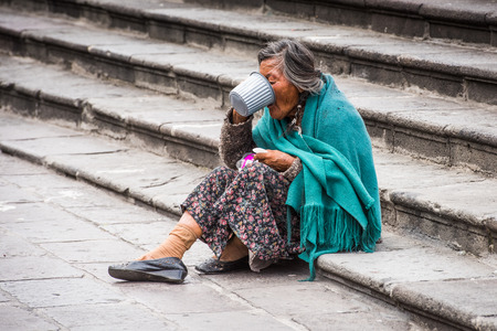 QUITO, ECUADOR - JAN 2, 2015: Unidentified Ecuadorian old lady eats on the stairs in the street. 71,9% of Ecuadorian people belong to the Mestizo ethnic groupのeditorial素材