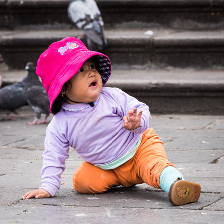 QUITO, ECUADOR - JAN 2, 2015: Unidentified Ecuadorian little girl crowls on the ground. 71,9% of Ecuadorian people belong to the Mestizo ethnic groupのeditorial素材
