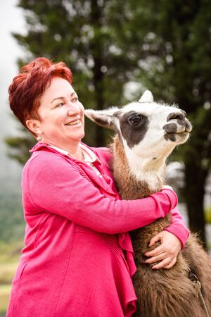 RIOBAMBA, ECUADOR - JAN 7, 2015: Unidentified Ecuadorian tourist hugs a lama. Lama is a popular kind of animal in Ecuadorのeditorial素材