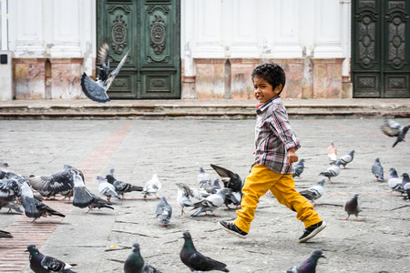 CUENCA, ECUADOR - JAN 9, 2015: Unidentified Ecuadorian boy plays with pigeons. 71,9% of Ecuadorian people belong to the Mestizo ethnic groupのeditorial素材