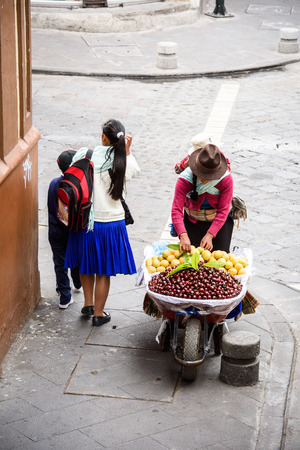 CUENCA, ECUADOR - JAN 9, 2015: Unidentified Ecuadorian woman in traditional clothes sells cherries. 71,9% of Ecuadorian people belong to the Mestizo ethnic groupのeditorial素材