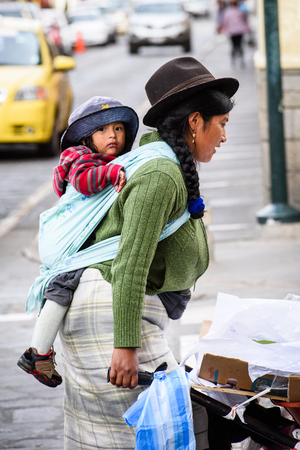 CUENCA, ECUADOR - JAN 9, 2015: Unidentified Ecuadorian woman carries a baby in the street. 71,9% of Ecuadorian people belong to the Mestizo ethnic groupのeditorial素材