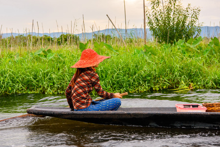 Burmese girl in bamboo boat sails over the Inle Sap,a freshwater lake located in the Nyaungshwe Township of Taunggyi District of Shan State, Myanmarの写真素材