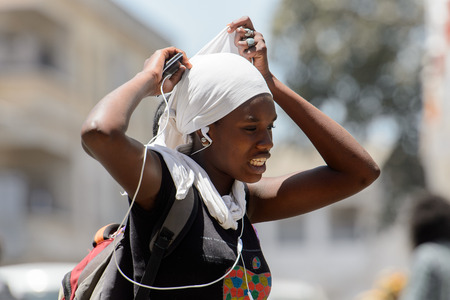 SAINT LOUIS, SENEGAL - APR 24, 2017: Unidentified Senegalese woman in white headscarf listens to...