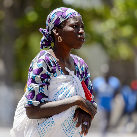 SAINT LOUIS, SENEGAL - APR 24, 2017: Unidentified Senegalese woman in traditional clothes and headscarf looks ahead in the centre of Saint Louis, one of the major cities in Senegalのeditorial素材