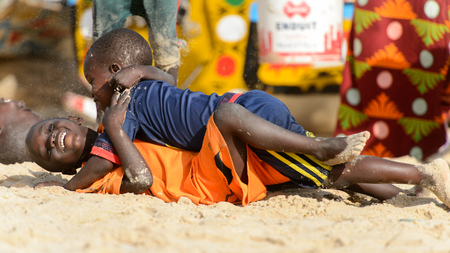 KAYAR, SENEGAL - APR 27, 2017: Unidentified Senegalese little boys lie on the sand while playing on the coast of the Atlantic Ocean. Many Kayar people work in portのeditorial素材