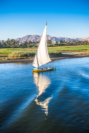 LUXOR, EGYPT - NOV 30, 2014: Felluca and its reflection over the river NIle near Luxor. Nile is 6,853 km long. The Nile is an "international" river shared by eleven countriesのeditorial素材