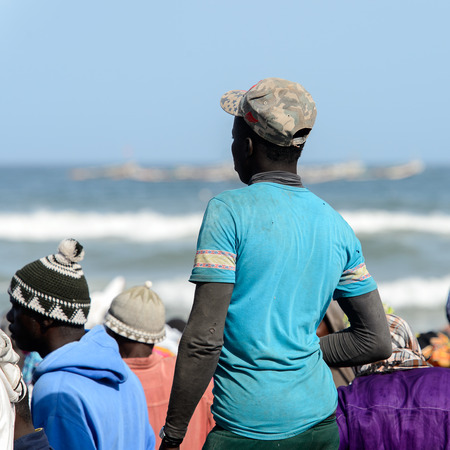 KAYAR, SENEGAL - APR 27, 2017: Unidentified Senegalese man in blue shirt stands on the coast of the Atlantic Ocean. Many Kayar people work in portのeditorial素材