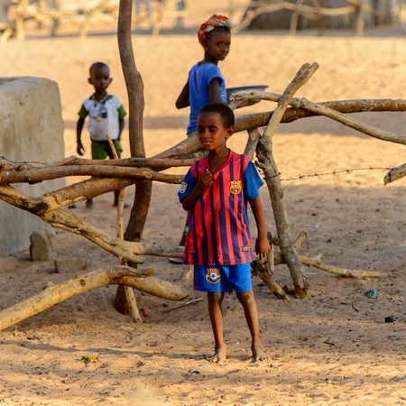 FERLO DESERT, SENEGAL - APR 25, 2017: Unidentified Fulani little boy in striped shirt stands in the...