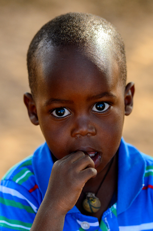 FERLO DESERT, SENEGAL - APR 25, 2017: Unidentified Fulani little boy in blue shirt puts his fingers into his mouth . Fulanis (Peul) are the largest tribe in West African savannahsのeditorial素材