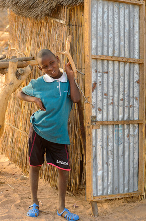 FERLO DESERT, SENEGAL - APR 25, 2017: Unidentified Fulani little boy in blue shirt stands near the shack. Fulanis (Peul) are the largest tribe in West African savannahsのeditorial素材