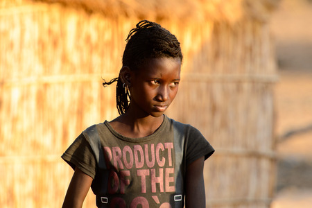 FERLO DESERT, SENEGAL - APR 25, 2017: Unidentified Fulani girl with braids walks along the street. Fulanis (Peul) are the largest tribe in West African savannahsのeditorial素材