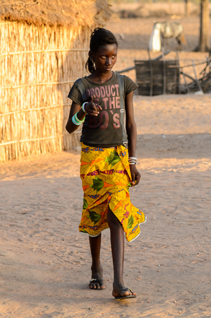 FERLO DESERT, SENEGAL - APR 25, 2017: Unidentified Fulani girl with braids walks along the street. Fulanis (Peul) are the largest tribe in West African savannahsのeditorial素材