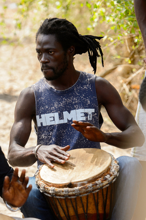 KASCHOUANE, SENEGAL - APR 29, 2017: Unidentified Diola man plays on drums in Kaschouane village. Diolas are the ethnic group predominate in the region of Casamanceのeditorial素材