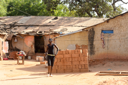 ZIGUINCHOR, SENEGAL - APR 28, 2017: Unidentified Senegalese man in black clothes with sunglasses walks along the street. Still many people in Senegal live in povertyのeditorial素材