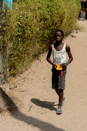 KASCHOUANE, SENEGAL - APR 29, 2017: Unidentified Diola little boy walks along the street in Kaschouane village. Diolas are the ethnic group predominate in the region of Casamanceのeditorial素材