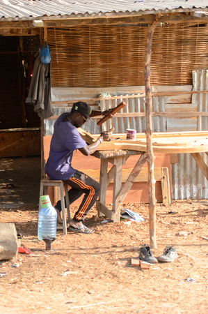 ZIGUINCHOR, SENEGAL - APR 28, 2017: Unidentified Senegalese man works with wood. Still many people in Senegal live in povertyのeditorial素材