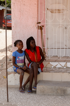 ZIGUINCHOR, SENEGAL - APR 28, 2017: Unidentified Senegalese girls sit on the porch. Still many people in Senegal live in povertyのeditorial素材