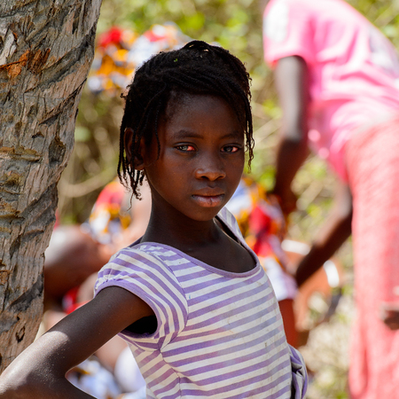 KASCHOUANE, SENEGAL - APR 29, 2017: Unidentified Diola girl with braids in striped shirt stands in Kaschouane village. Diolas are the ethnic group predominate in the region of Casamanceのeditorial素材