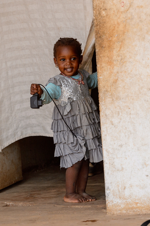 DAKAR, SENEGAL - APR 27, 2017: Unidentified Senegalese little girl in beautiful dress looks out of the curtain in the Village des Arts in Dakarのeditorial素材