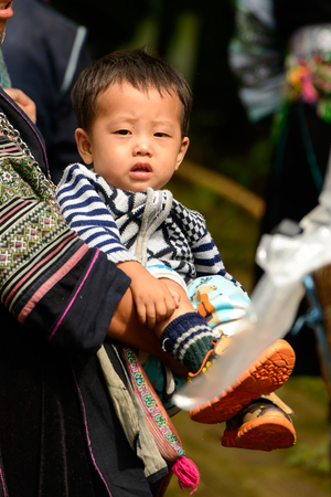 SAPA, VIETNAM - SEP 20, 2014: Unidentified Hmong woman in the traditional costume carries her little baby. Hmong people is a minority ethnic group living in Sapaのeditorial素材