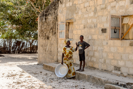 KASCHOUANE, SENEGAL - APR 29, 2017: Unidentified Diola woman in traditional clothes stands with a basin in Kaschouane village. Diolas are the ethnic group predominate in the region of Casamanceのeditorial素材