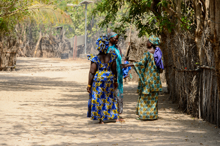 KASCHOUANE, SENEGAL - APR 29, 2017: Unidentified Diola women in traditional clothes walk along the street in Kaschouane village. Diolas are the ethnic group predominate in the region of Casamanceのeditorial素材
