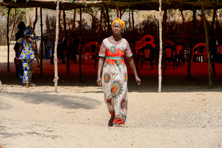 KASCHOUANE, SENEGAL - APR 29, 2017: Unidentified Diola woman in traditional clothes walks along the street in Kaschouane village. Diolas are the ethnic group predominate in the region of Casamanceのeditorial素材