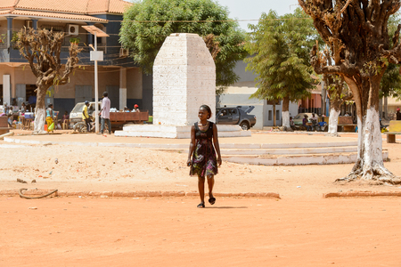 CANCHUNGO, GUINEA BISSAU - MAY 3, 2017: Unidentified local woman walks across the road in the centre of Canchungo, one of the major cities of the countryのeditorial素材