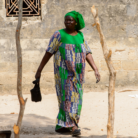 KASCHOUANE, SENEGAL - APR 29, 2017: Unidentified Diola woman in traditional clothes walks along the...