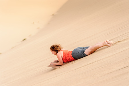 SOSSUSVLEI, NAMIBIA - JAN 6, 2016: Unidentified girl slides down the dune in Namib-Naukluft National Park, Namibia. A park is part of the Namib Desert,the oldest desertのeditorial素材