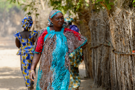 KASCHOUANE, SENEGAL - APR 29, 2017: Unidentified Diola woman in traditional clothes walks along the street in Kaschouane village. Diolas are the ethnic group predominate in the region of Casamanceのeditorial素材